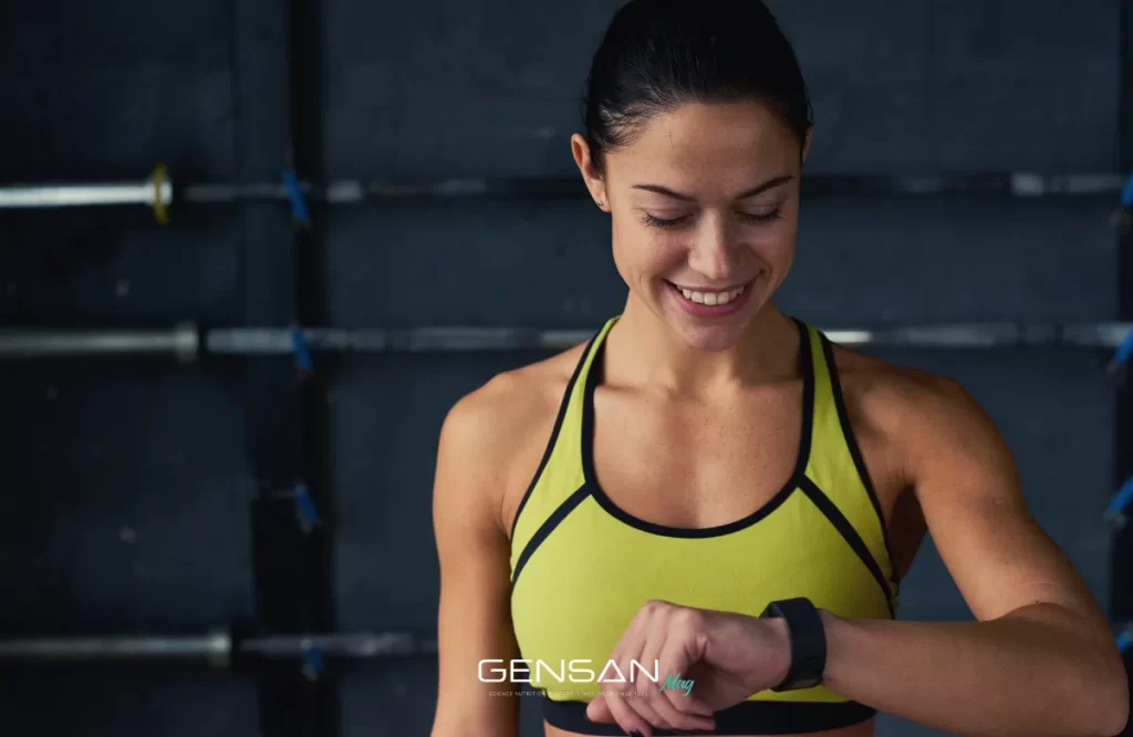 ragazza guarda l'orologio a polso per capire quando assumere gli integratori sportivi