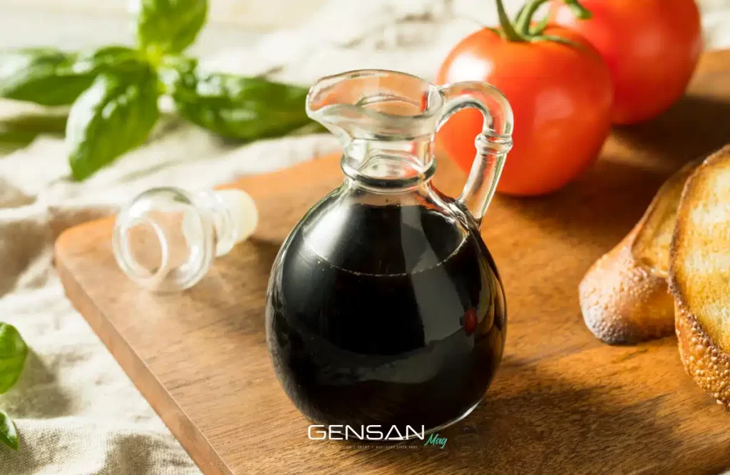 brocca di aceto balsamico su un tavolo con pane pomodori e basilico