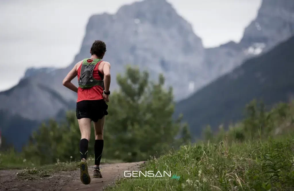 Sportivo dal fisico ectomorfo corre lungo un sentiero in montagna