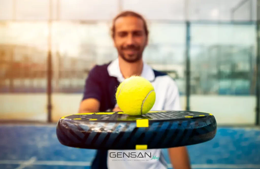 giocatore di padel con racchetta e pallina gialla in primo piano